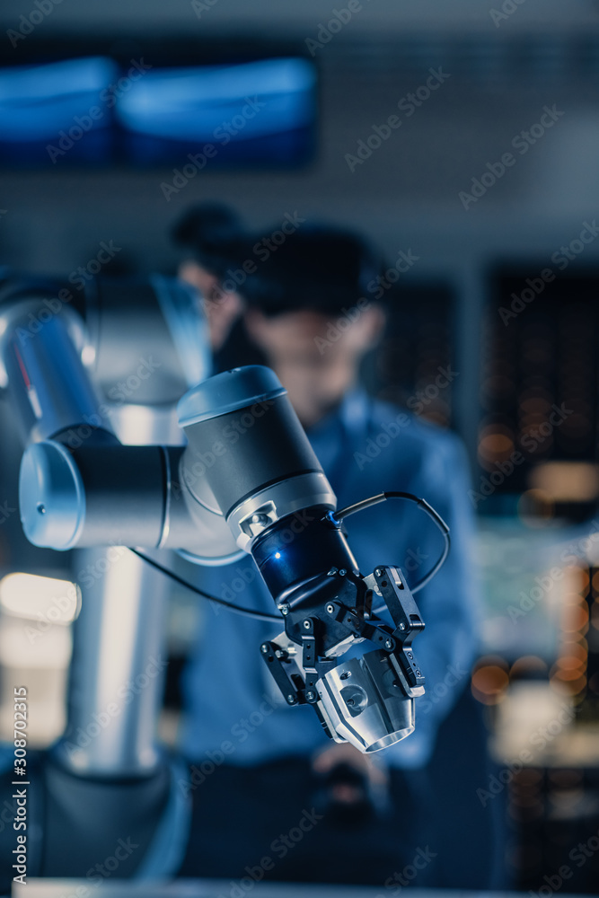 Aufkleber Vertical Close-up Shot of a Futuristic Robotic Arm Controlled by Professional Development Engineer with Virtual Reality Headset and Joysticks in a High Tech Research Laboratory with Modern Equipment