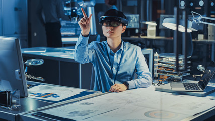 Professional Japanese Development Engineer is Working in a AR Headset, Making Gestures of Touching Virtual Graphics Pieces in the High Tech Research Laboratory with Modern Computer Equipment.