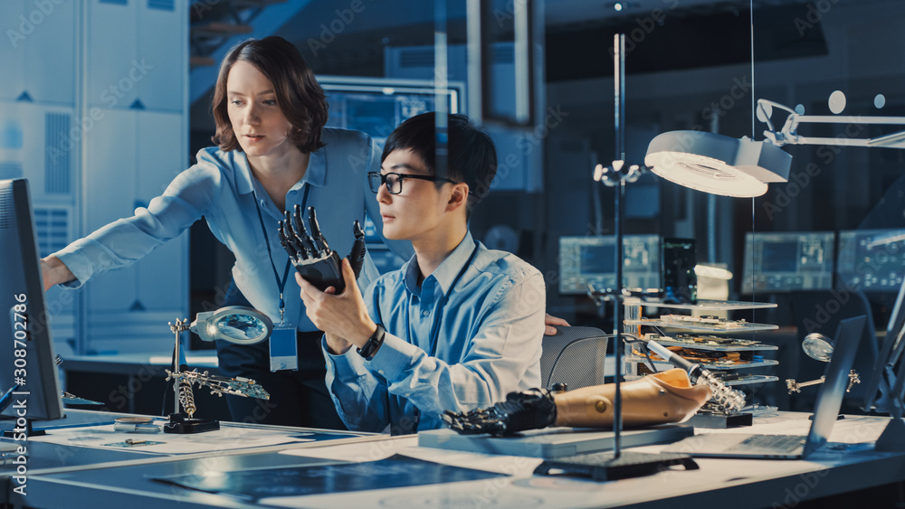 Leinwandbilder Technological Prosthetic Robot Arm is Tested by Two Professional Development Engineers in a High Tech Research Laboratory with Modern Futuristic Equipment. Man and Female Compare Data on a PC