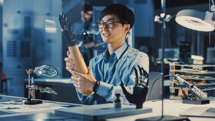 Futuristic Prosthetic Robot Arm Being Tested by a Professional Japanese Development Engineer in a High Tech Research Laboratory with Modern Computer Equipment. He is Satidfied with the Result.