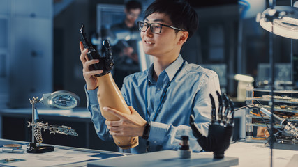 Futuristic Prosthetic Robot Arm Being Tested by a Professional Japanese Development Engineer in a High Tech Research Laboratory with Modern Computer Equipment. He is Satidfied with the Result.