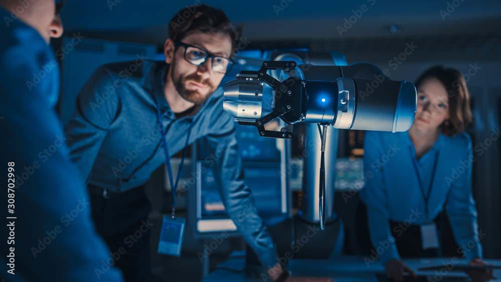 Leinwandbilder futuristic metal robotic arm picking up a metal object and moving it. senior engineer talks through 