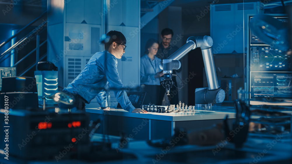 Poster Professional Japanese Development Engineer is Testing an Artificial Intelligence Interface by Playing Chess with a Futuristic Robotic Arm. They are in a High Tech Modern Research Laboratory.
