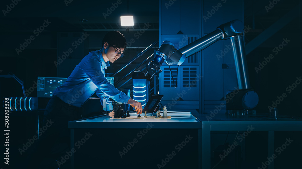Aufkleber Japanese Development Engineer is Testing an Artificial Intelligence Interface by Playing Chess with a Futuristic Robotic Arm. They are in a High Tech Modern Research Laboratory with Low Key Light.