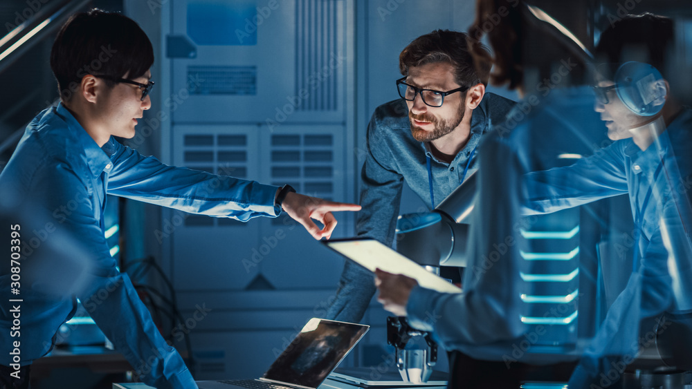 Leinwandbilder Diverse Team of Engineers with Laptop and a Tablet Analyse and Discuss How a Futuristic Robotic Arm Works and Moves a Metal Object. They are in a High Tech Research Laboratory with Modern Equipment.