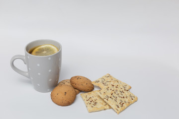 In a porcelain Cup tea with lemon and cookies on a white background
