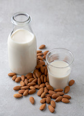 Almond drink milk in glass bottle surrounded by almonds nuts