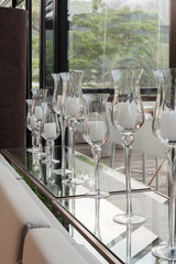 Crystal glasses with candles stand by a large window.