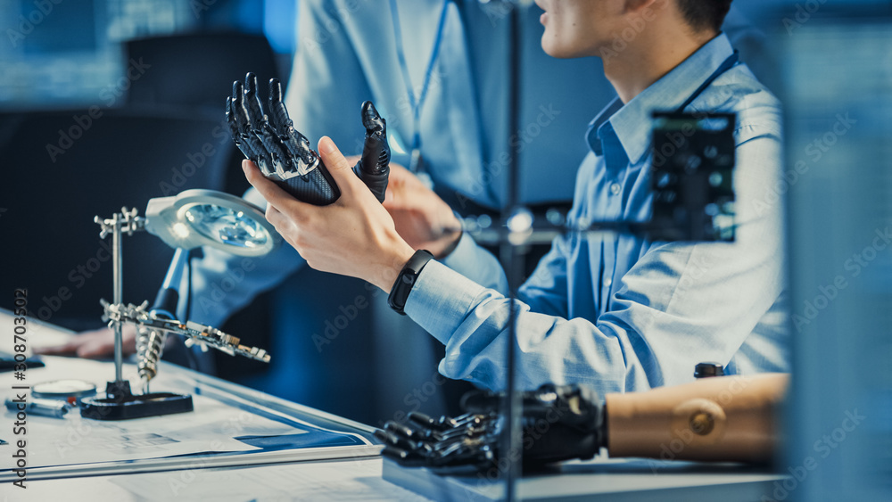 Fototapete Technological Prosthetic Robot Arm is Tested by Two Professional Development Engineers in a High Tech Research Laboratory with Modern Futuristic Equipment. Compare Data on a Personal Computer.