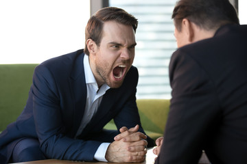 Angry businesswoman screaming at opponent, showing aggression at meeting