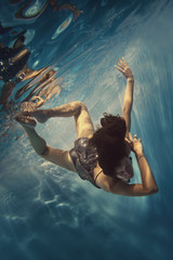 Fototapeta na wymiar A girl in a brilliant suit swims underwater