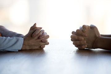 Close up clasped female hands of two businesswomen negotiate at table