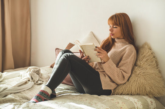 Attractive Young Woman Is Reading A Book At Home. Thoughtful Girl Reading Important Book.