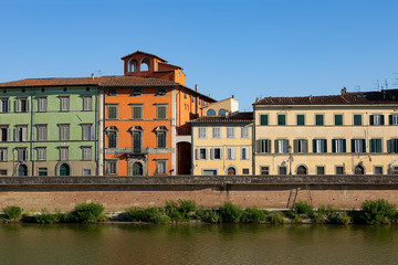 Fototapeta na wymiar Colorful Historical buildings by Arno river. Row of traditional houses with shutters in Pisa, Italy. Summer day in Tuscany. Old city