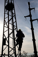Silhouette of a worker climbing on a electrical pole