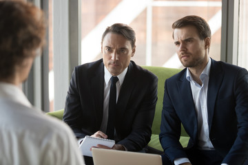 Two serious doubting hr managers listening to candidate in job interview