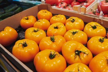 Big yellow heirloom tomatoes in the box at the market place. Fresh healthy vegetables in the grocery store.