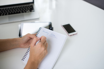 A blonde hair businesswoman working in her workstation. Businesswoman working at workplace. Woman working in home office. Woman sitting at desk and working with laptop and glass of water.
