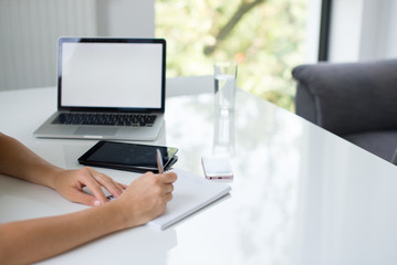 A blonde hair businesswoman working in her workstation. Businesswoman working at workplace. Woman working in home office. Woman sitting at desk and working with laptop and glass of water.