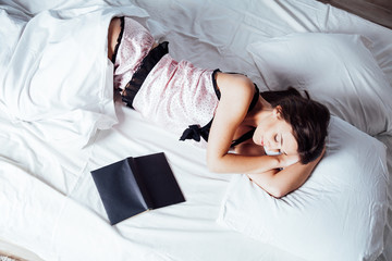 girl in pajamas lying on the bed with a book before bed
