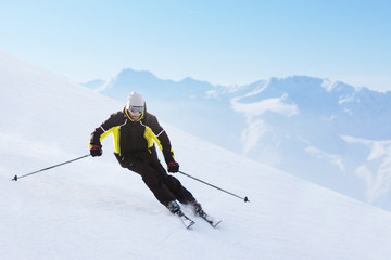 Alpine skier on piste running downhill