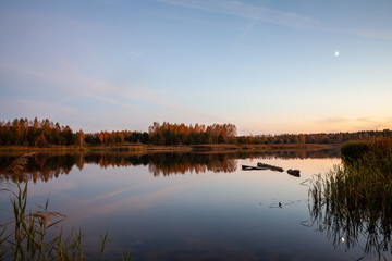 Ozierany Lake during evening. Small moon reflected in the water on the right side of the picture.