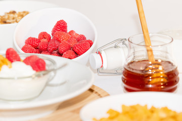 Healthy balanced Breakfast of cereals and dairy products with berries and honey on a white background.