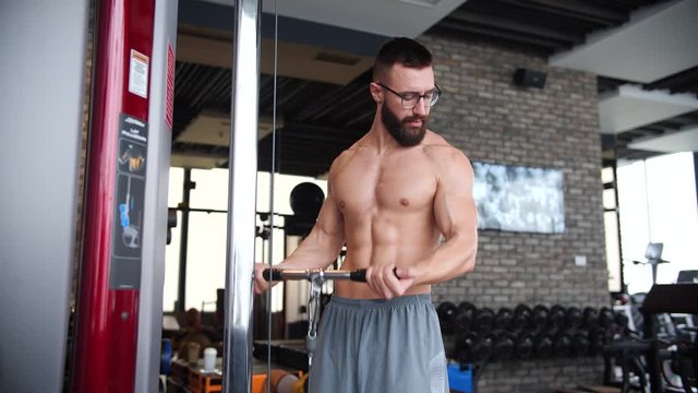 Shirtless athletic geek man doing Outside grip cable biceps workout.