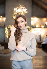 Beautiful woman (girl) with long hair dressed in a warm fashion long sleeve sweater among Christmas or New Year lights