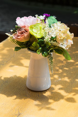 Artificial flowers in a vase on the table.
