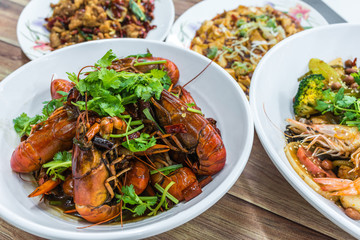 China, Chongqing Sichuan spicy dried chilli small lobsters, among other dishes in the background. Chinese food photography at Chinese restaurant.