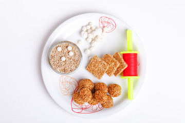 Til Gul OR Sweet Sesame Laddu in Plate with Fikri for Indian festival Makar Sankranti over white background 