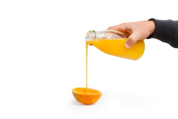 Mano sirviendo zumo de naranja de botella sobre un fondo blanco liso y aislado. Vista de frente. Copy space