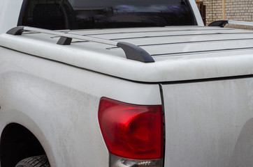 White dusty pickup truck in the parking lot. Close-up of an American SUV. Closed luggage compartment. Back view. Without people. © Mikhail