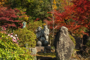 京都、松ヶ崎にある松ヶ崎大黒天（妙円寺）の大黒天と恵比寿の石像、後ろの観音様と紅葉の風景