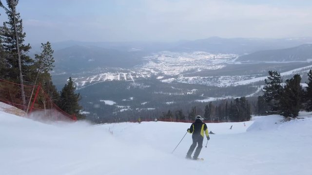 Young adult recreational skier enjoys idyllic perfect weather in cold winter. Skiing alone on perfectly groomed ski piste at ski resort. Located at the top of the mountain