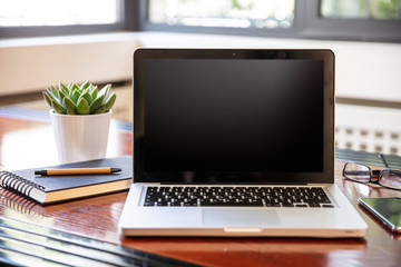 Laptop with black blank screen on a wooden desk