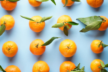 Fresh orange tangerines with leaves, on a blue background. Flat lay.