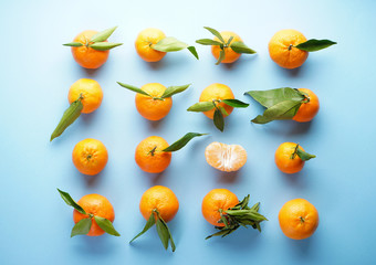 Fresh orange tangerines with green leaves, on a blue background. Flat lay.