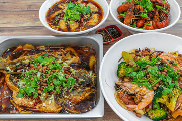 Assorted traditional dishes such as Fragrant Hotpot, Spicy boiled fish, mini lobsters, Chongqing grilled fish. Flat lay top down view of table of authentic Asia, China Sichuan Hunan food.
