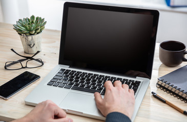 Laptop with black blank screen on a wooden desk