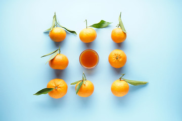 Fresh orange tangerines with leaves, on a blue background with orange jam. Flat lay