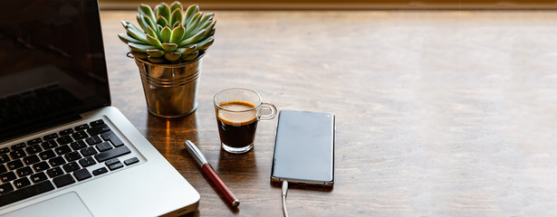 Workplace. Computer laptop and mobile phone on a wood office desk, banner, copy space - Powered by Adobe