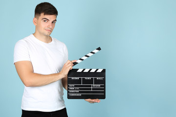 Young man with black clapper board on blue background
