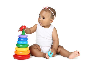 American baby girl sitting and playing with toys on white background