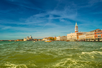 Colorful panoramic view of Doge Palace, Campanile and San Marco square from busy Grand Canal water during sunset, Venice, Italy, summer time