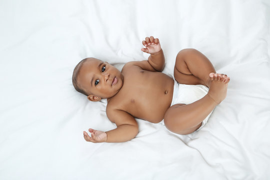 American baby girl lying on white bed