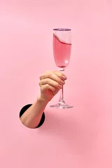 Foto op Canvas Rose wine glass in a female's hand from the hole in the wall. © artjazz
