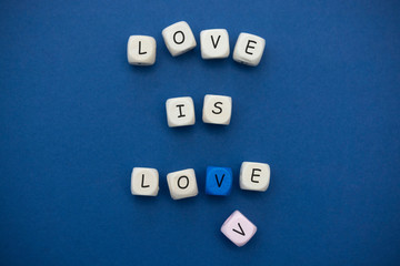 Love is love message written on wooden blocks over blue background.