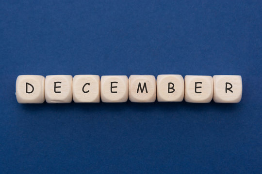 December lettering. Wooden blocks with december word over clasic blue blackground. Copy space.